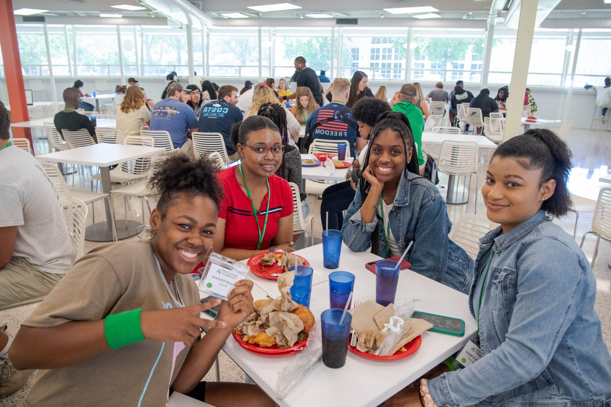 4 young ladies finishing lunch at a table in the cafeteria.