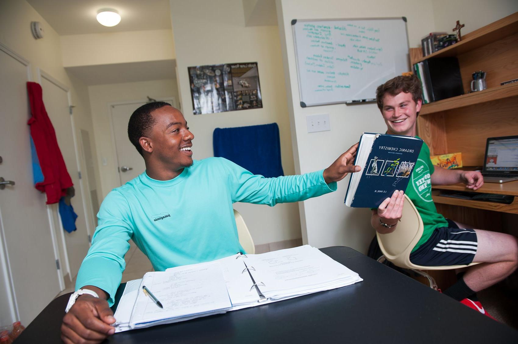 2 young men completing homework in residence hall room.